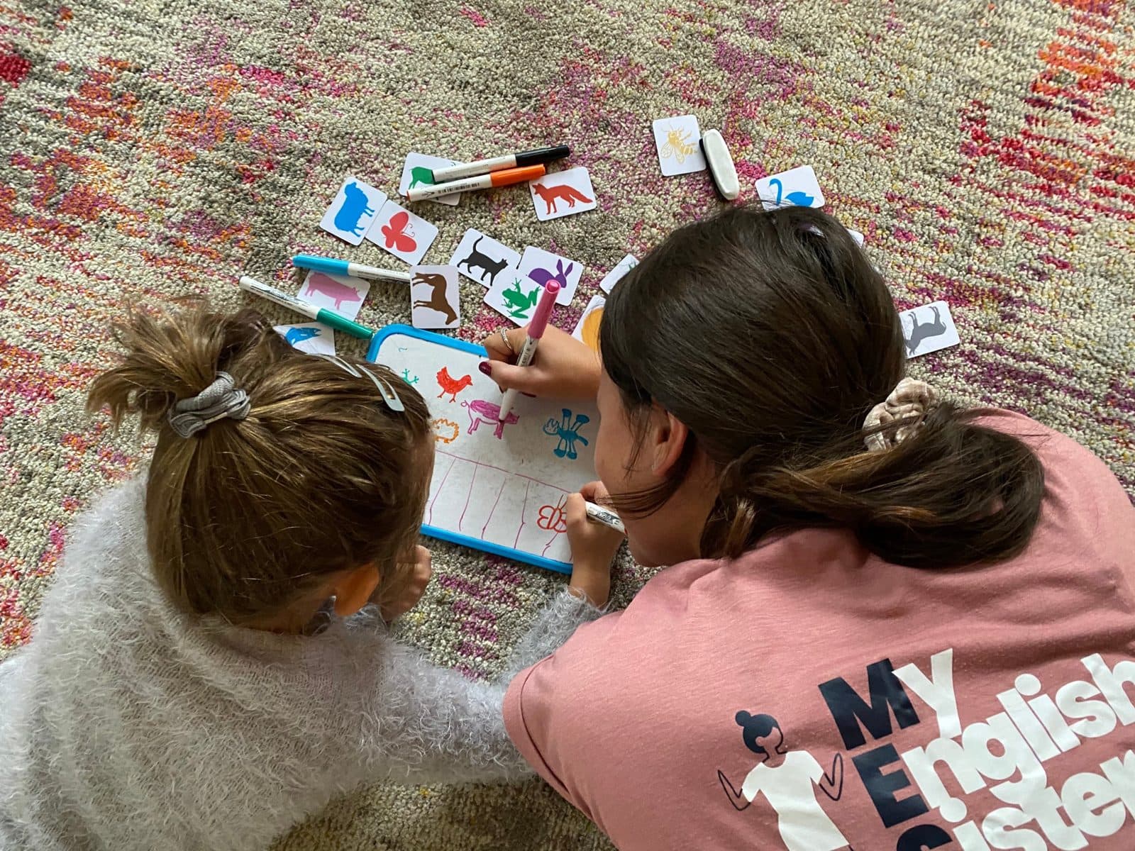 A My English Sister assistant drawing animals with a child on a whiteboard